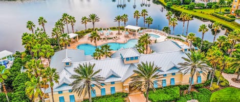 A resort with a large pool, palm trees, and a lake view.