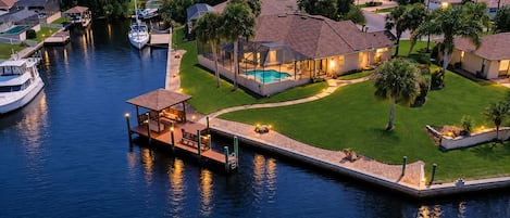 A residential area with a dock, a swimming pool, and houses with well-maintained lawns.