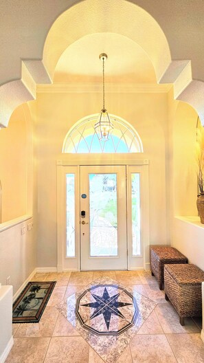 A foyer with a geometric patterned floor, a star design, a chandelier, and a door with frosted glass panels. - Captain's Key Waterside Retreat - Boat Dock! Awesome Pool! (Palm Coast)