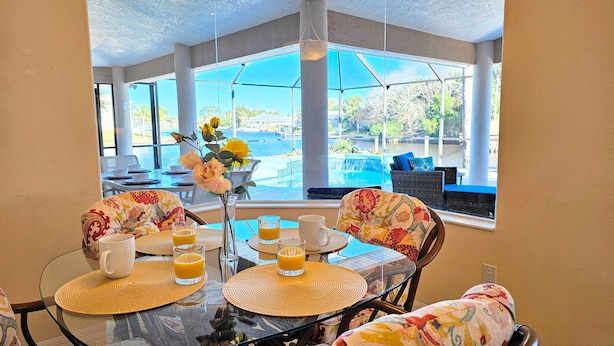 A dining area with a view of a pool and outdoor seating. - Captain's Key Waterside Retreat - Boat Dock! Awesome Pool! (Palm Coast)