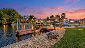 A waterfront property with a dock, a gazebo, and a boat.