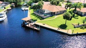 A residential area with a dock, boats, and houses with lawns and trees. - Captain's Key Waterside Retreat - Boat Dock! Awesome Pool! (Palm Coast)