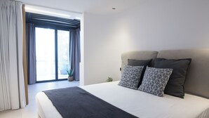 A modern hotel room with a large bed, a window with curtains, and a potted plant. - Penthouse in the Heart of Glyfada (Glifada)