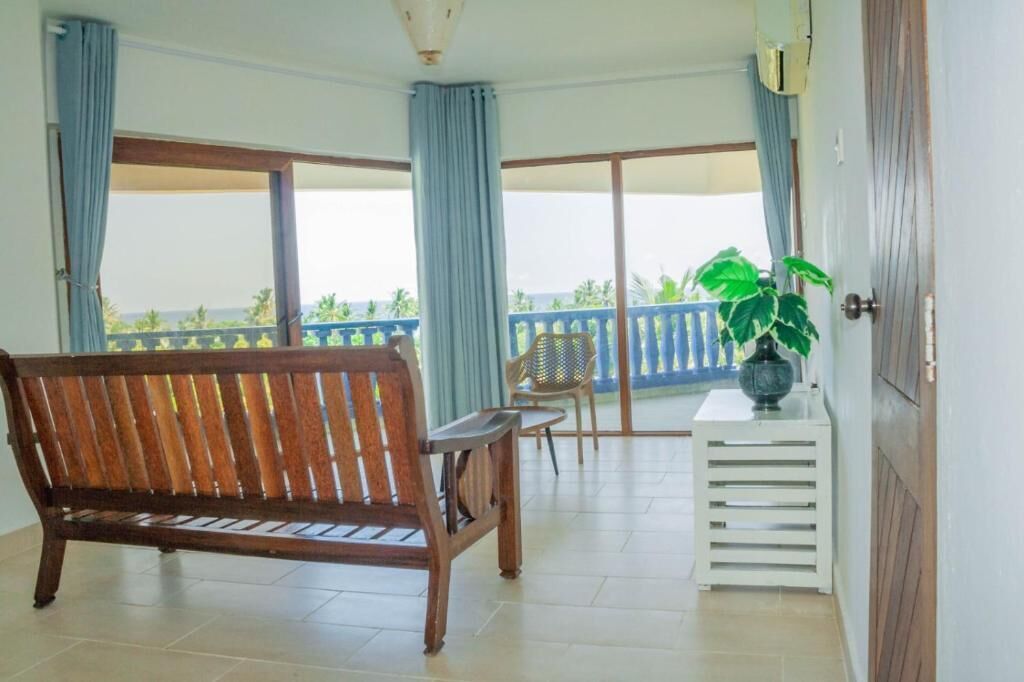 A balcony with a wooden bench, a chair, and a potted plant.