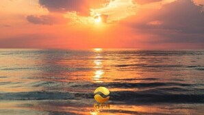 Un coucher de soleil sur l’océan, avec un ballon de plage au premier plan.