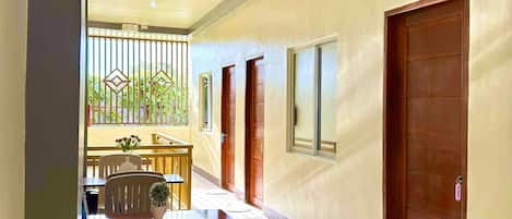 A hallway with a dining area, a wooden door, and a small potted plant on a table.