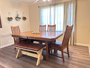 Una sala da pranzo con un tavolo di legno, quattro sedie, una panca e tre fioriere pensili.