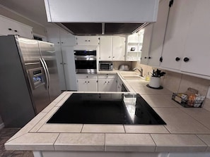 Una cucina moderna con isola centrale, forno integrato, microonde e frigorifero.
