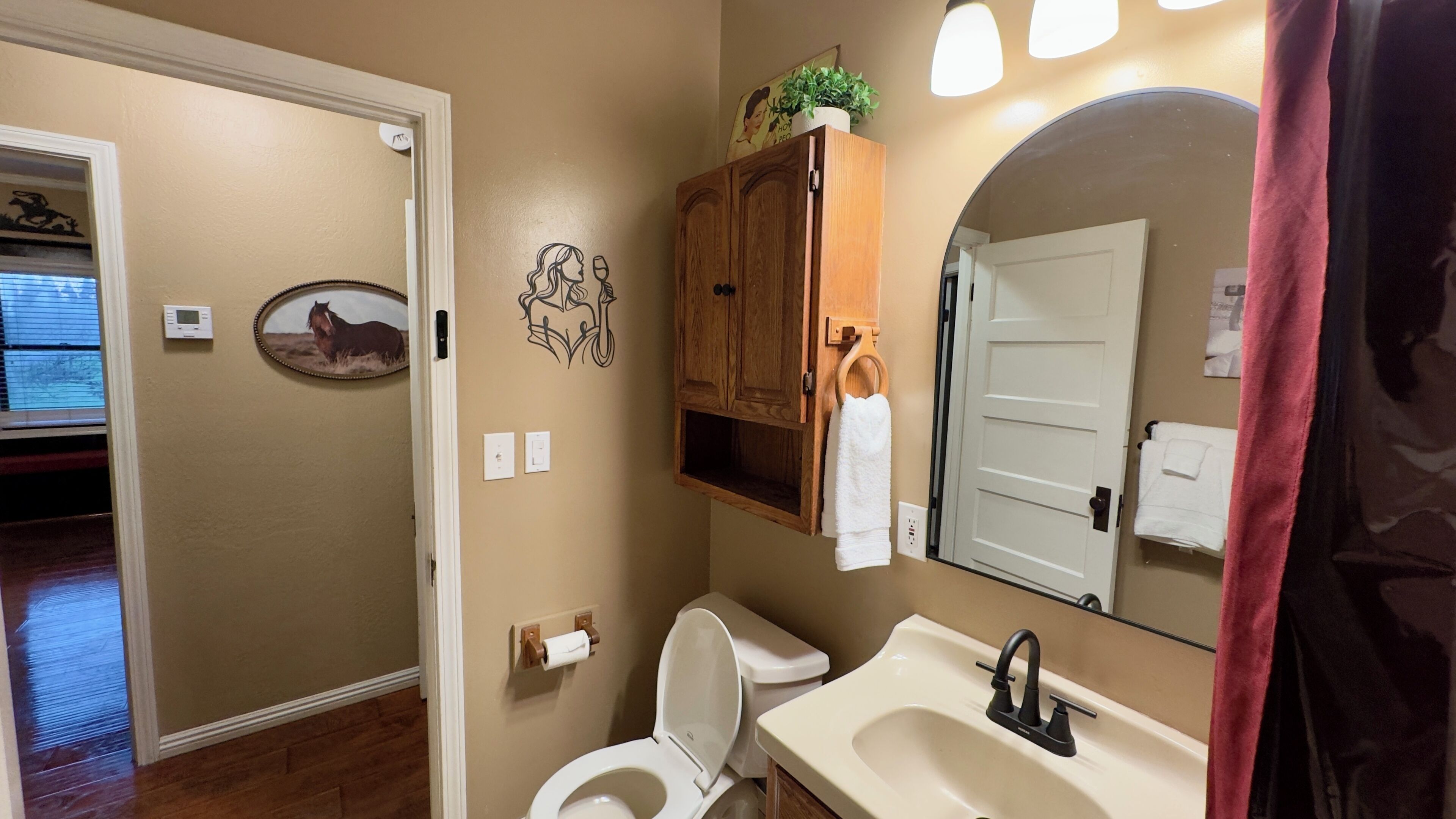 A bathroom with a toilet, sink, and wooden cabinet.