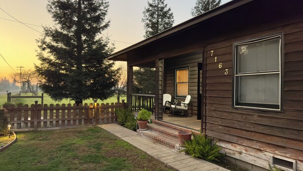 Eine Holzhütte mit Veranda, einem Stuhl und einem Tisch.