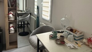 A compact kitchen with a dining area, a built-in bookshelf, and a window with blinds. - Umbertos rooms (Jerzu)