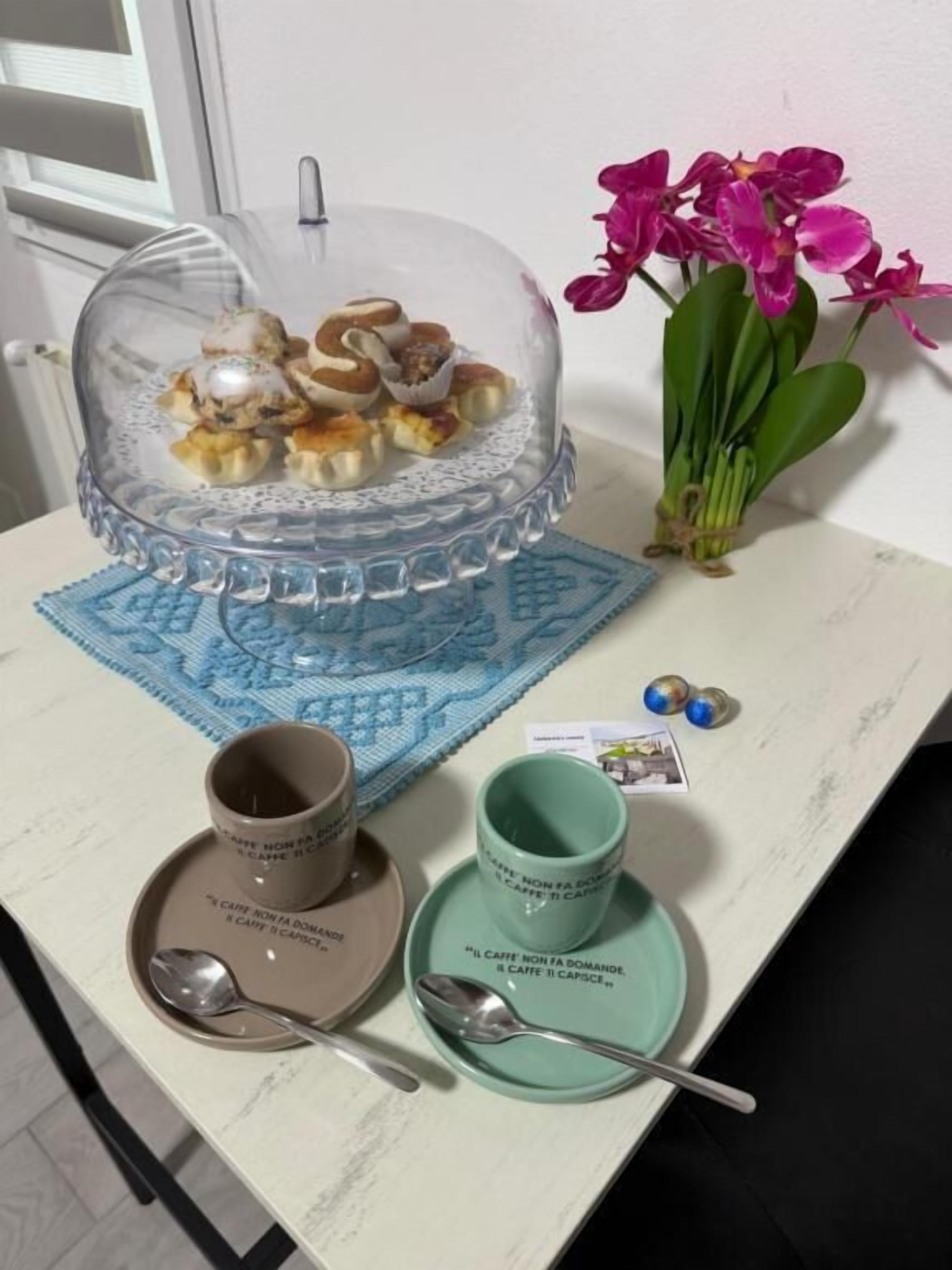 Una mesa de comedor con una cubierta de vidrio transparente, un posavasos azul y dos tazas de café con sus platillos a juego.