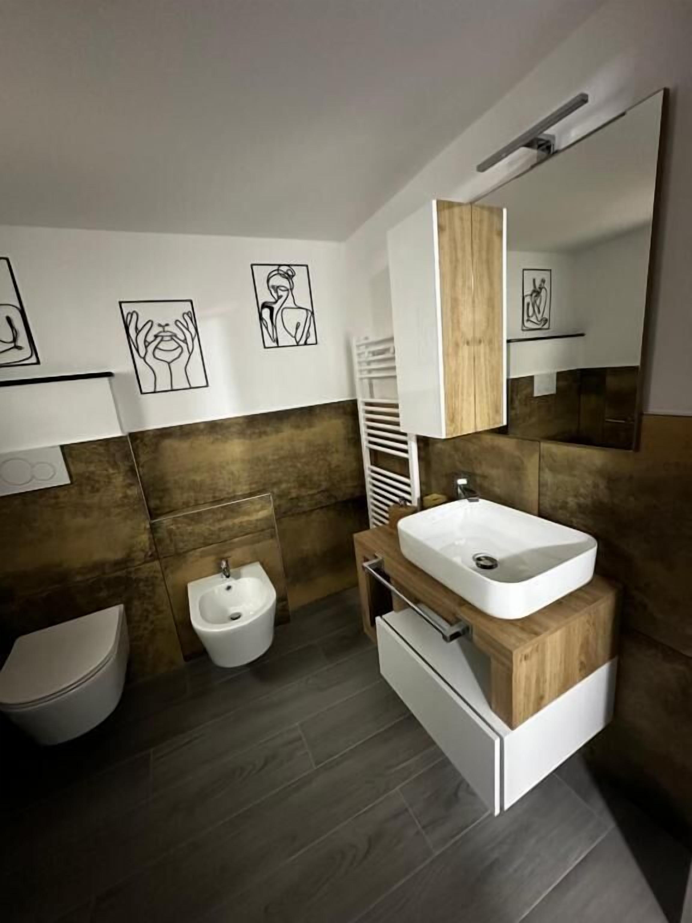 Un baño moderno con un tocador de madera, un bidé y un inodoro.