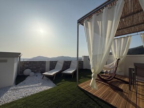 Une terrasse sur le toit offrant une vue dégagée sur les montagnes, une plateforme en bois et un auvent blanc.