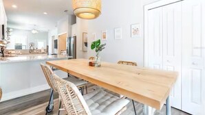 Uma sala de jantar moderna com mesa de madeira, cadeiras de vime e um lustre.
