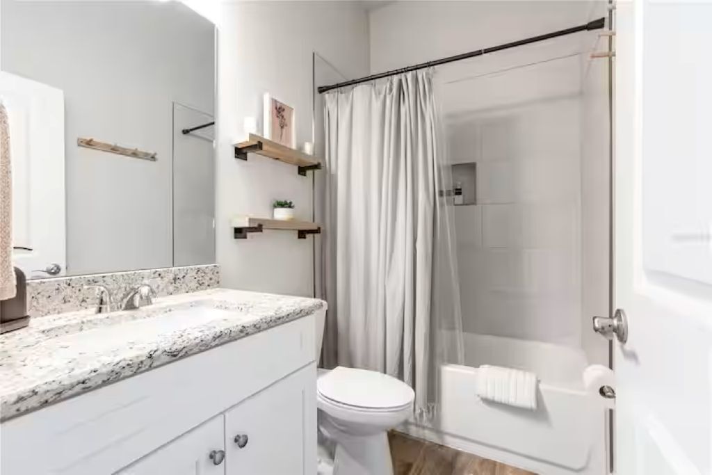 A modern bathroom with a shower, toilet, and vanity.