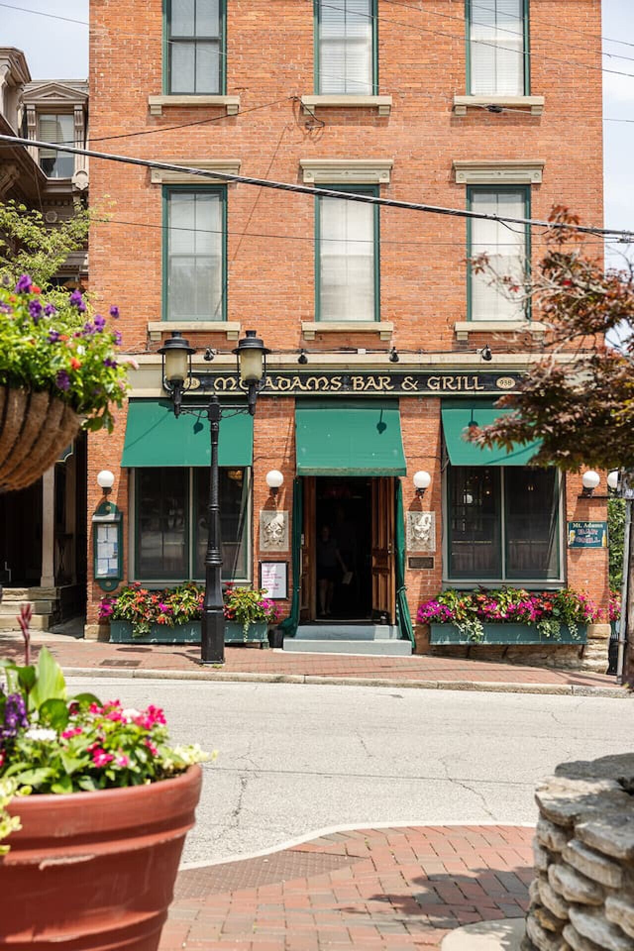 Un bâtiment en briques surmonté d’une marquise verte et portant l’enseigne « Old Adams Bar & Grill ».
