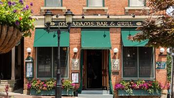 Un bâtiment en briques surmonté d’une marquise verte et portant l’enseigne « Old Adams Bar & Grill ».