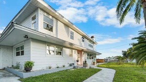 Kaksikerroksinen talo, jossa on kuisti, pieni puutarha ja päällystetty kävelytie.