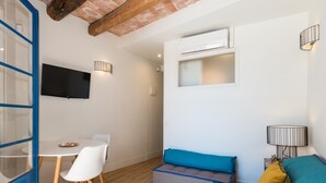 Un espacio de estar moderno con comedor, sofá y televisor montado en la pared.