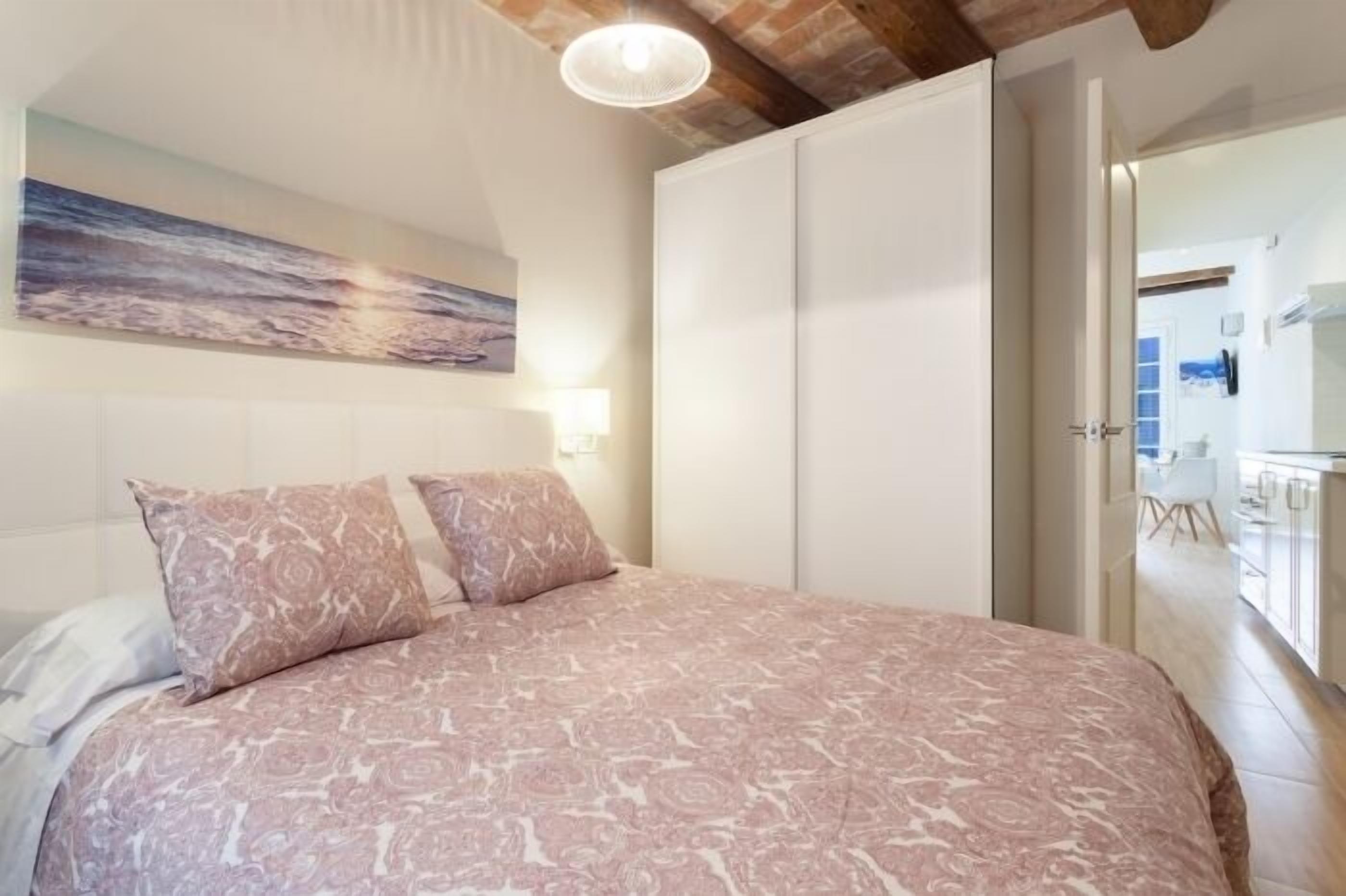 Ein Schlafzimmer mit Bett, Kleiderschrank und einem Bild an der Wand.