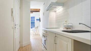 Una cocina estrecha con gabinetes blancos, una encimera y una estufa a la vista.