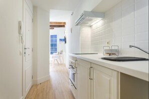 A narrow kitchen with white cabinets, a countertop, and a visible stove. - Rental unit in Sitges · ★4.83 · 1 bedroom · 1 bed · 1 bath (Sitges)