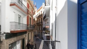 Una calle estrecha flanqueada por edificios, con una puerta azul a la derecha y gente caminando.