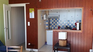 Une cuisine compacte avec des meubles en bois, un four à micro-ondes encastré et un petit évier.
