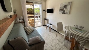 A cozy living room with a sofa, a small table, and a TV. - Apartment for 4 at 50m from the beach (Argelès-sur-Mer)