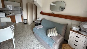 A compact room with a kitchenette, a sofa, a small table, and a mirror. - Apartment for 4 at 50m from the beach (Argelès-sur-Mer)