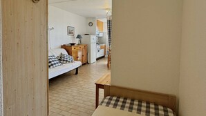 Un espacio habitable compacto con sofá, una mesita, una cocina con microondas y lavadora.