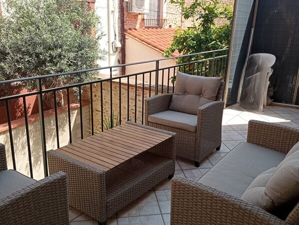 A balcony with wicker furniture, including a sofa and a table. - Village house with air conditioning, terrace, 6-8 pers, Canet-en-Roussillon (Canet-en-Roussillon)