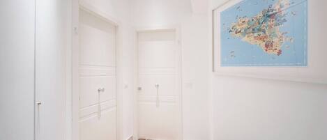 A hallway with white doors, a map on the wall, and two doormats with names.