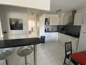 A compact kitchen with white cabinets, a black countertop, and a small dining area with two stools. - Modern 3-room apartment on marina for 6 people (Canet-Plage)