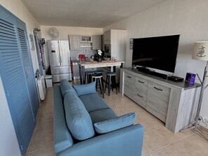 Un espace de vie compact comprenant un canapé, un coin cuisine et un téléviseur.