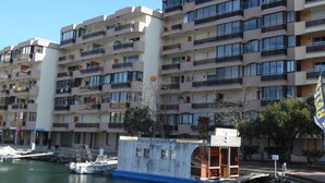 Un edificio residencial de varios pisos con balcones y un pequeño barco amarrado al borde del agua.