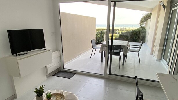 Ein modernes Wohnzimmer mit Flachbildfernseher, einer Couch und einem Essbereich mit Tisch und Stühlen.