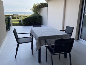 A patio with a table and chairs, a view of the sea, and a lamp post. - Renovated 1-bedroom with terrace, beach access, Canet-Plage (Canet-Plage)