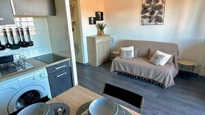 A compact living space with a kitchenette, a sofa, and a dining area. - Cozy studio beach access, balcony and parking (Le Barcarès)