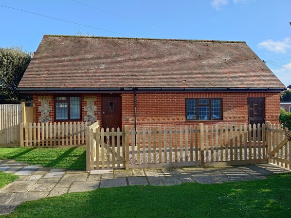 A two-story brick house with a tiled roof, a wooden picket fence, and a stone pathway leading to the entrance. - 1 bedroom apartment in prime location close to town centre and the beach. (Selsey)
