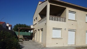 Un bâtiment à deux étages doté d’un balcon, d’un espace extérieur couvert et d’un garage.