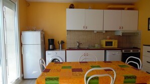 Une cuisine compacte avec des meubles blancs, un four à micro-ondes, une machine à café et un lave-linge.