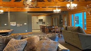 A spacious living area with a leather sofa, a dining table, and a kitchen in the background.