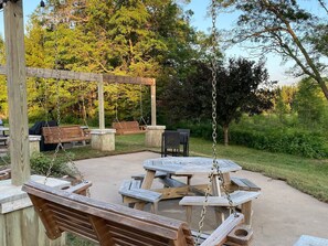 An outdoor patio with wooden benches and tables, surrounded by greenery. - Larrabee Lake Retreat - The Lodge & Cottage (New Auburn)
