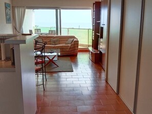A living room with a sofa, a coffee table, and a TV. There is a balcony with a view of the sea. - Modern T2 Sea View, 3 Stars, Private Parking, Near Beach (Canet-en-Roussillon)