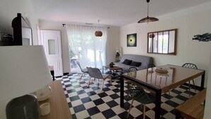 A dining area with a checkered floor, a table with chairs, a sofa, and a hanging light fixture. - Single-storey air-conditioned house close to beach in Canet-en-Roussillon (Canet-en-Roussillon)