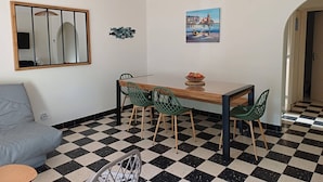A dining area with a checkered floor, a wooden table, green chairs, a mirror, and a painting. - Single-storey air-conditioned house close to beach in Canet-en-Roussillon (Canet-en-Roussillon)