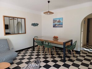 A dining area with a checkered floor, a wooden table, green chairs, a mirror, and a painting. - Single-storey air-conditioned house close to beach in Canet-en-Roussillon (Canet-en-Roussillon)