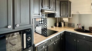 A kitchen with dark cabinets, a microwave, a toaster, and a patterned backsplash. - Apartment 4 people with terrace, AC, parking, 200m from beach (Le Barcarès)
